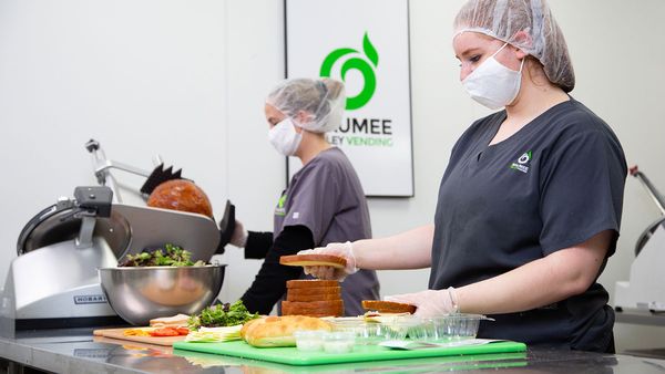 Two Maumee Valley Group employees preparing fresh food (sandwiches).